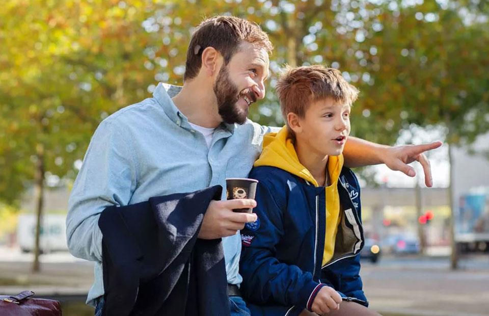 father and son discussing outdoors while enjoying a casual moment in a park