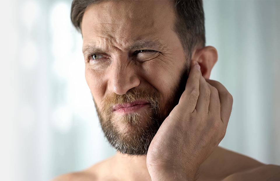 person holding their ear and experiencing discomfort