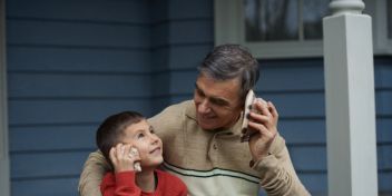 Father and son sharing a phone call on a porch