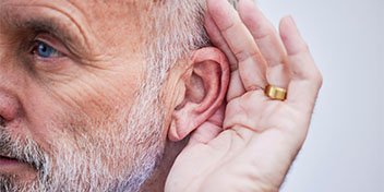 A close-up of an older adult’s ear with a hand cupped behind it, suggesting difficulty hearing. The image highlights hearing care concerns, suitable for promoting hearing tests and hearing aids.