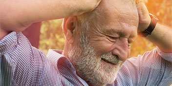 man experiencing tinnitus symptoms holding head outdoors