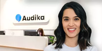 Hearing care professional at Audika clinic reception desk.