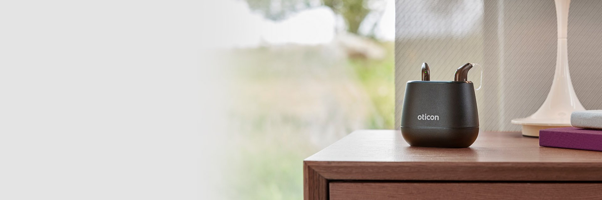 oticon intent hearing aid charger on a wooden table with a modern indoor setting