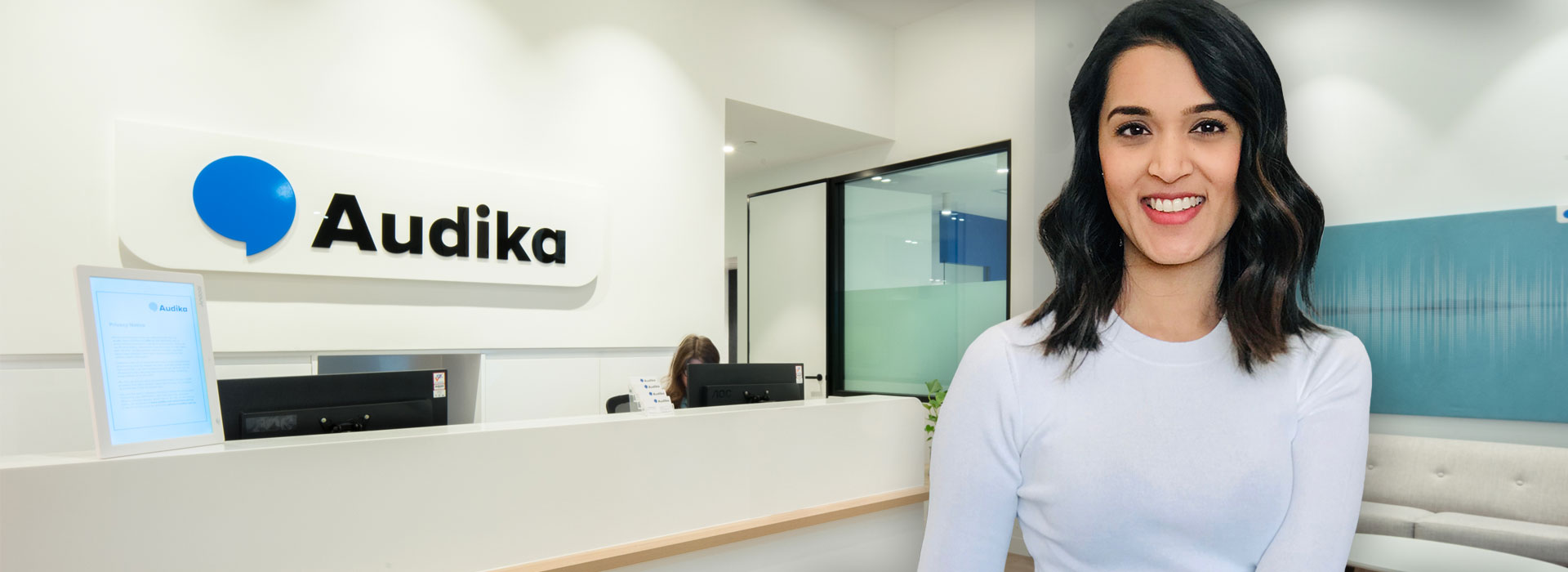 Reception area at an Audika hearing care clinic with staff in the background.