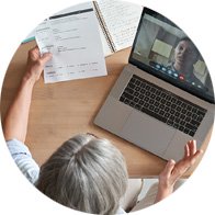 Senior professional participating in a video call while reviewing a document at a desk.