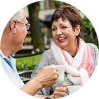 Older couple enjoying a conversation over coffee outdoors.