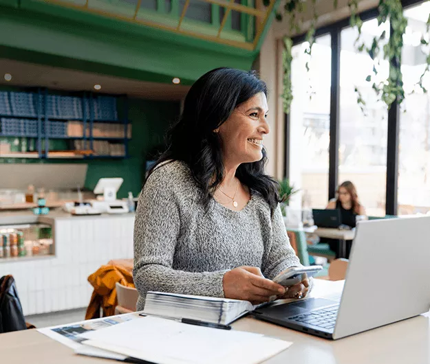 woman-using-smartphone-while-working-on-laptop-in-modern-cafe