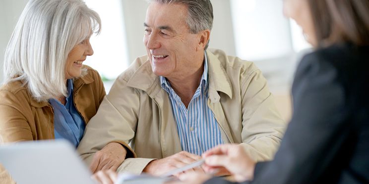 Happy couple discussing hearing care financing options with a professional