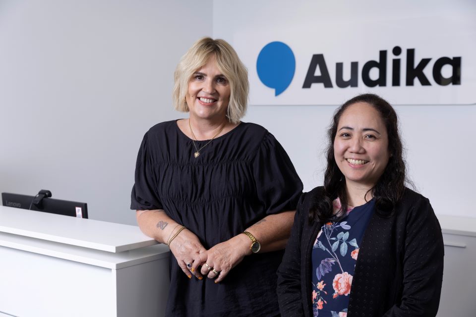 Hearing care professionals standing at the Audika reception desk.