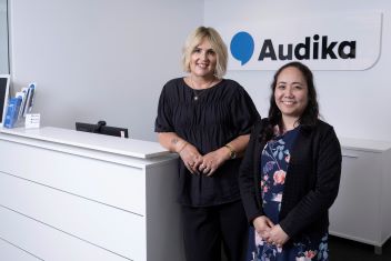 Hearing care professionals standing at the reception desk of the Audika Hamilton clinic.