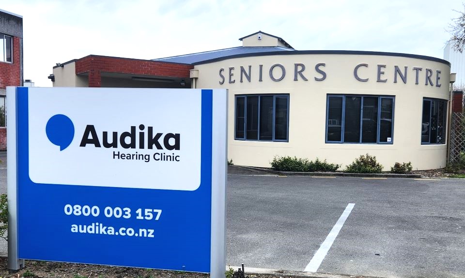 Audika Hearing Clinic Ashburton located at the Seniors Centre with contact information and website displayed on a sign in the parking area.