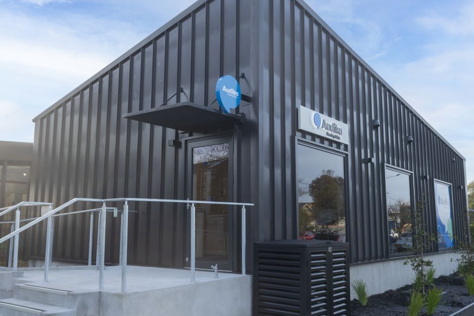 Audika hearing clinic exterior in Papanui, Christchurch, featuring modern architecture and signage.