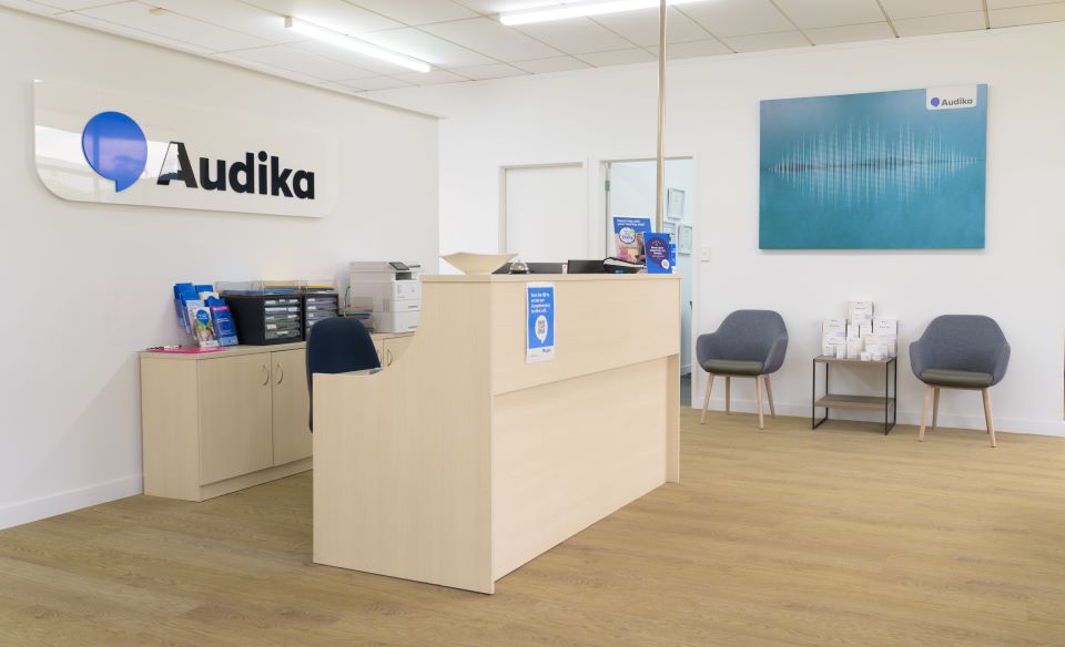 Audika Nelson hearing clinic reception area with modern design, seating, and branding.
