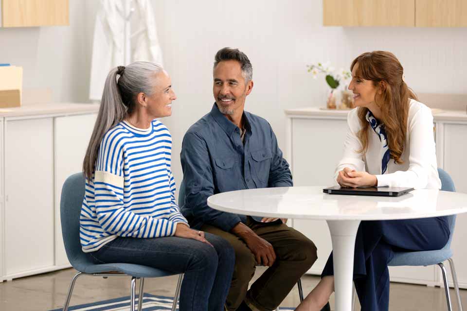 Hearing care specialist consulting with a couple in a modern hearing clinic setting.