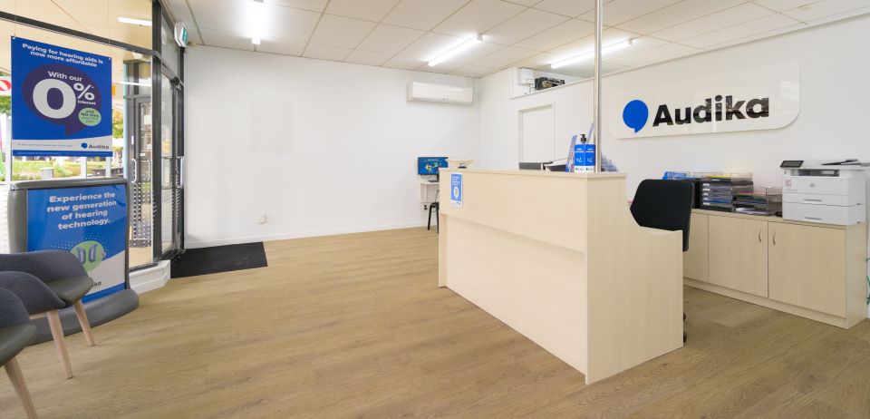 Reception area at Audika Nelson, featuring a clean, well-lit space with modern furnishings and promotional materials for hearing technology.