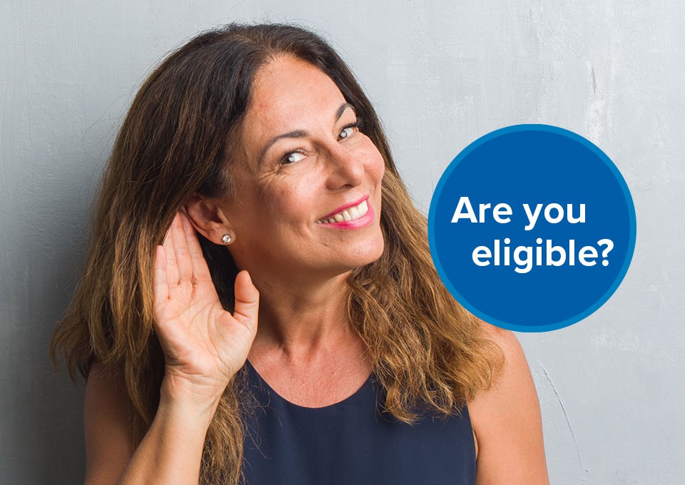 A woman with blurred facial features cups her ear while facing forward, symbolizing active listening, against a plain, light-gray background. A blue circle reads, 'Are you eligible?' promoting hearing care awareness.