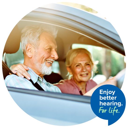 Man_and_woman_driving_in_car_smiling_with_text_below_enjoy_better_hearing_for_life