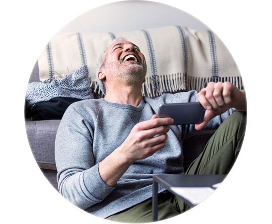 Oticon Zircon hearing aid user relaxing at home while engaging with a smartphone.