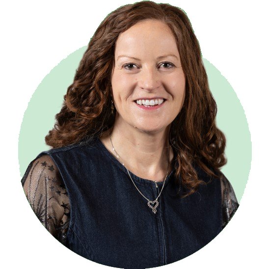 Hearing care clinician wearing a navy blouse with lace sleeves and a silver necklace, placed against a light green and white circular background.