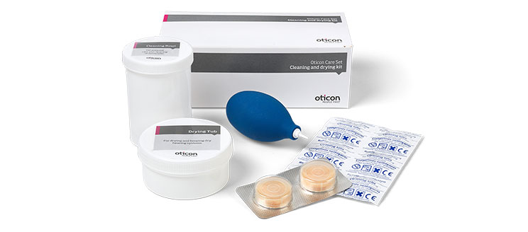 Oticon Care Set includes a cleaning and drying kit with a drying tub, air puffer, cleaning tablets, and accessories. The packaging displays ’Oticon’ branding, reflecting professional hearing aid maintenance tools.