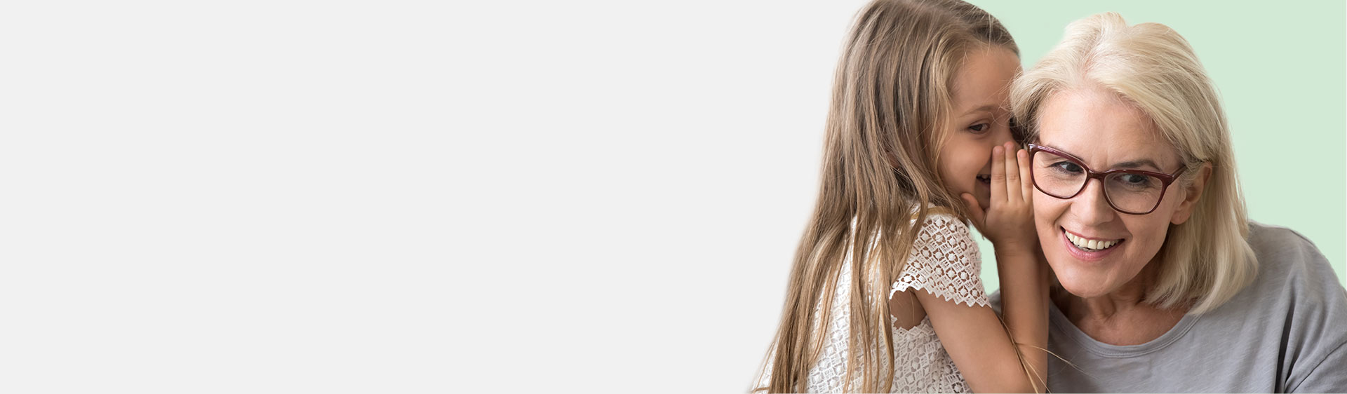 Little girl whispering into an older woman’s ear, symbolizing communication and connection.