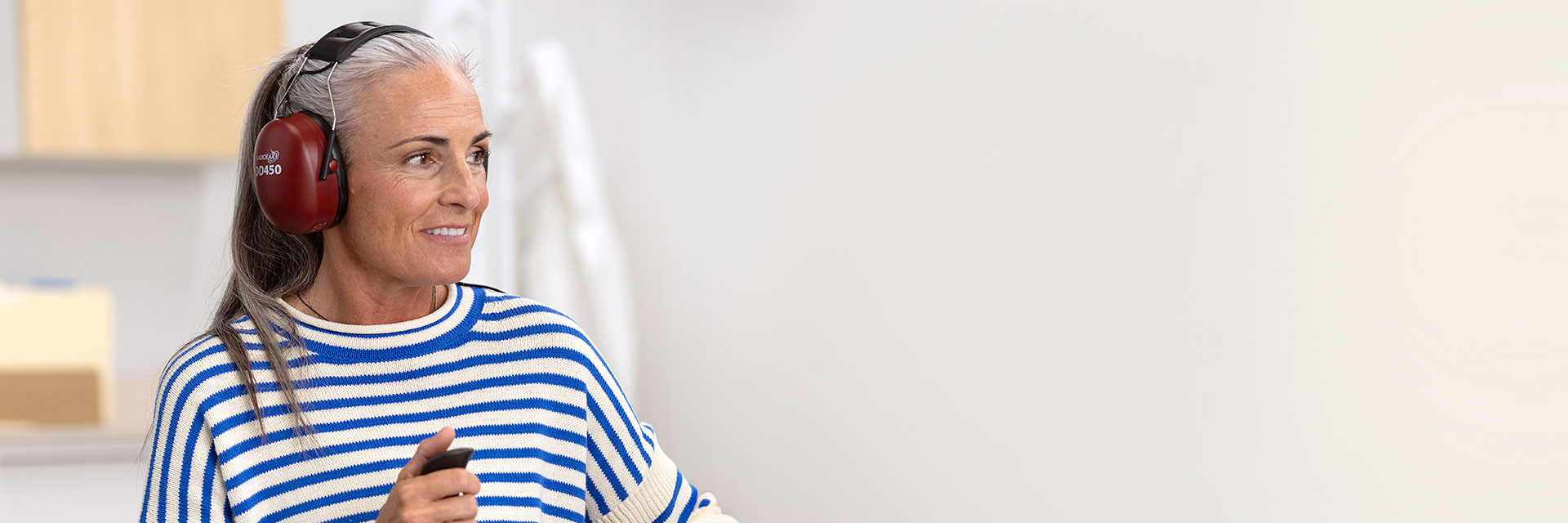 Man undergoing a hearing test while holding a response button in a modern, cozy environment.