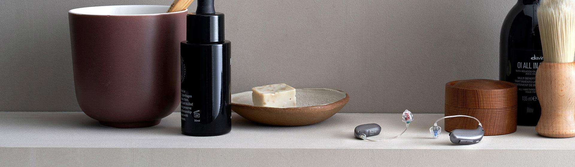 Digital hearing aids placed on a countertop alongside grooming products and accessories.