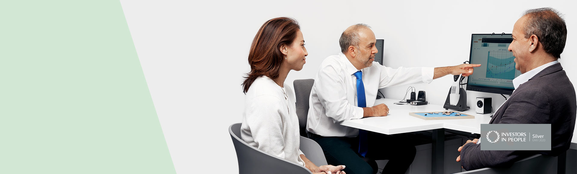 Audiologist explaining hearing test results to a couple in a clinic setting.