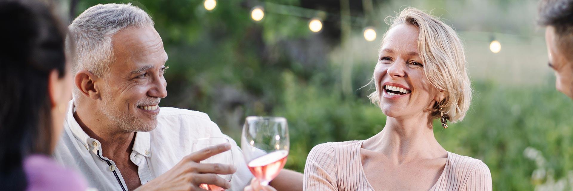 Happy man enjoying a meal with friends at an outdoor dinner party.