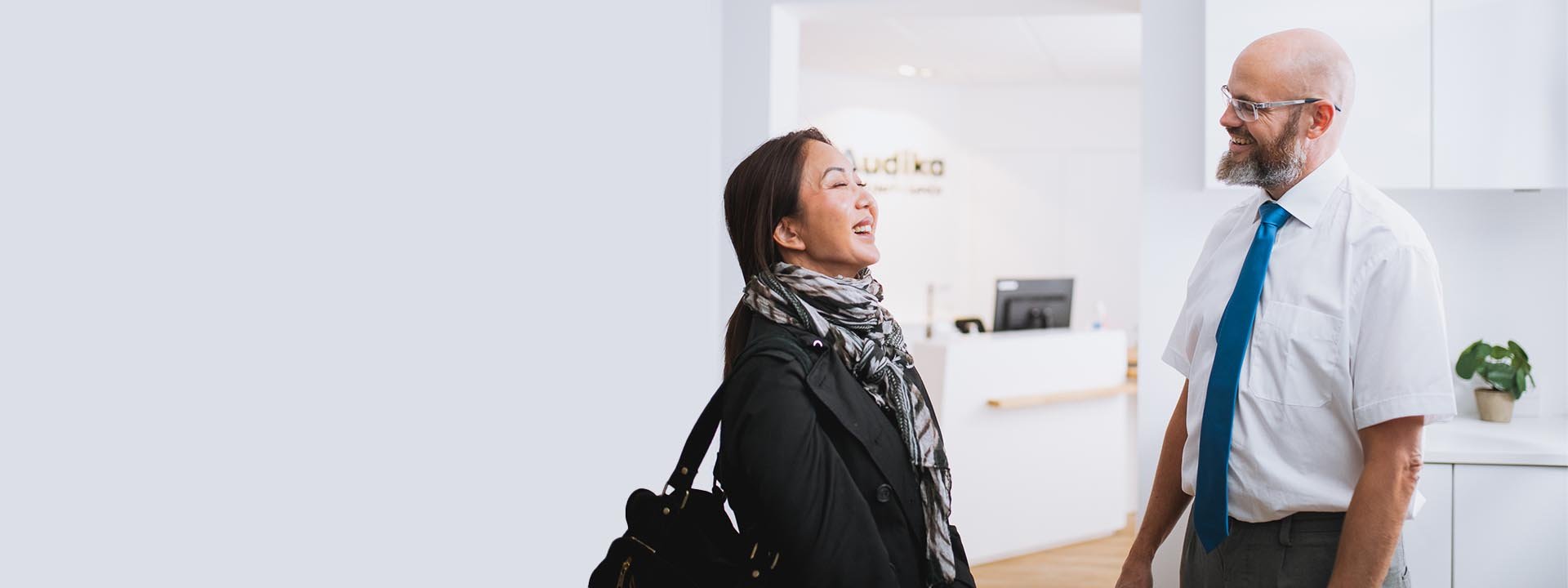 Woman consulting with a hearing care professional in a clinic reception area.