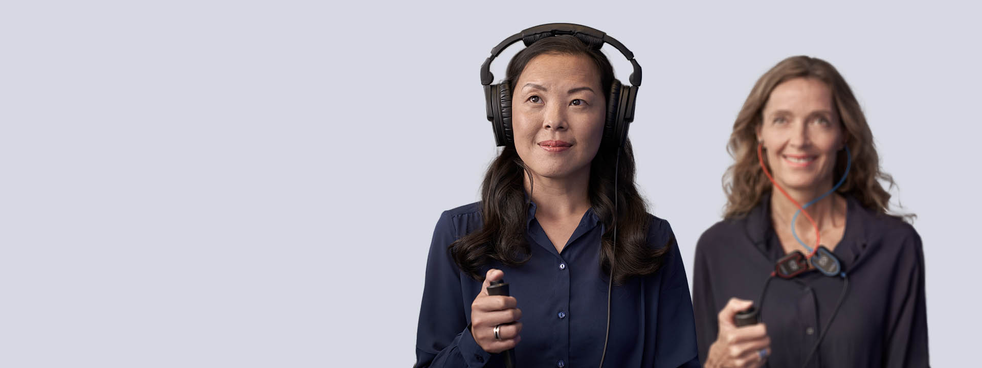 Two women undergoing a hearing test with headphones and response devices.