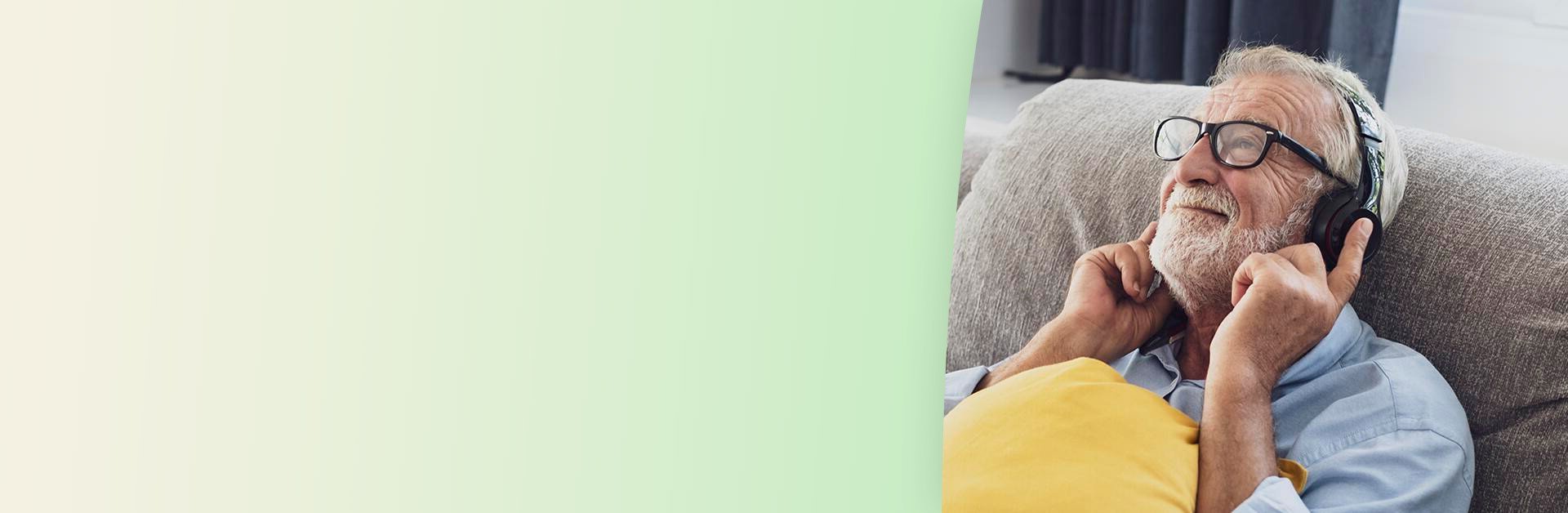 Senior man sitting on a couch wearing headphones.