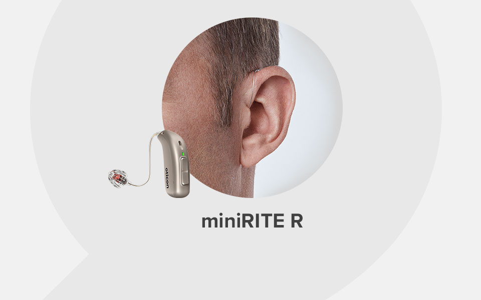 A discreet Oticon miniRITE R hearing aid is worn behind a man's ear, highlighting its sleek design and rechargeable feature against a neutral white backdrop. Text reads: 'miniRITE R.'