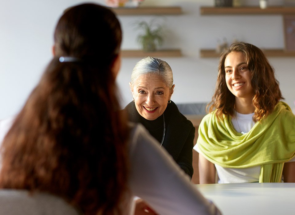 Woman attending a consultation with a hearing care specialist, accompanied by another individual.