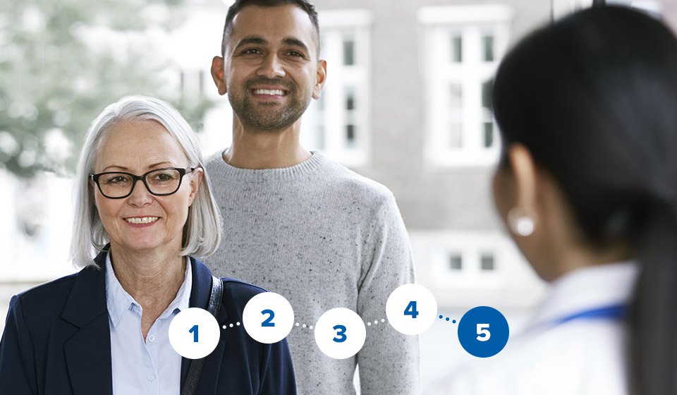 Audiologist greeting a man and woman at a hearing clinic.