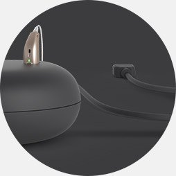 Connecting a hearing aid charger to a power source using an integrated cable.