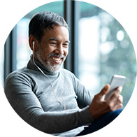 Man wearing earbuds and looking at his phone indoors