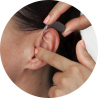 Placing a hearing aid behind the ear.