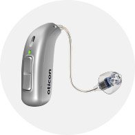 A sleek silver Oticon hearing aid with a slim receiver-in-canal design, green status indicator light, and clear earpiece, set against a plain white circular background.