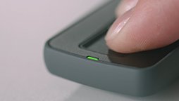 Finger pressing a button to connect hearing aids to a remote control.
