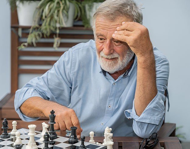 Man concentrating while playing chess outdoors.