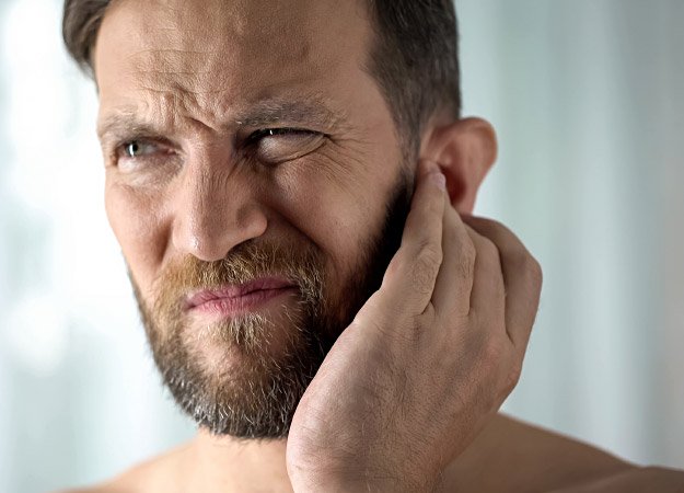 Man holding his ear due to tinnitus symptoms