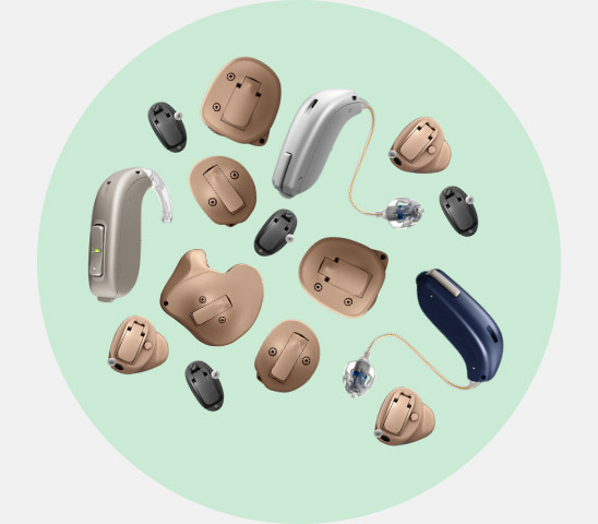 Various hearing aids, including behind-the-ear and in-the-ear models, are displayed on a light green circular background, showcasing different styles and sizes from beige, black, and blue color options. No text is present.