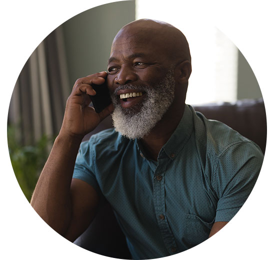 Man with a beard holding a phone to his ear while sitting indoors.