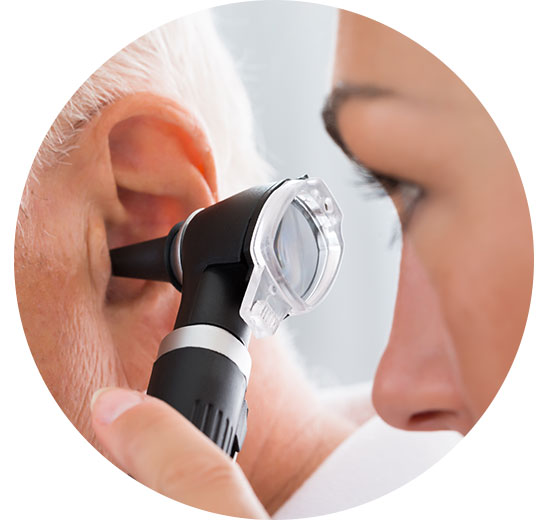 A healthcare professional examines an older adult’s ear using an otoscope, likely during a hearing test, within a clinical setting associated with Audika hearing care services. No visible text.