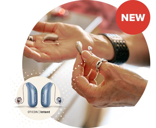 A pair of hands hold and examine sleek, modern hearing aids in a bright indoor setting. The image features Oticon Intent hearing aids, highlighted in a circular callout. ’NEW’ is prominently displayed in a red badge.